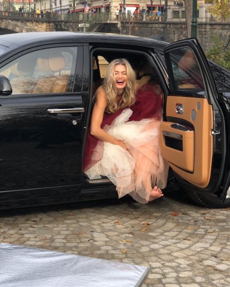 Paulina Porizkova  poses for a picture in her black car.